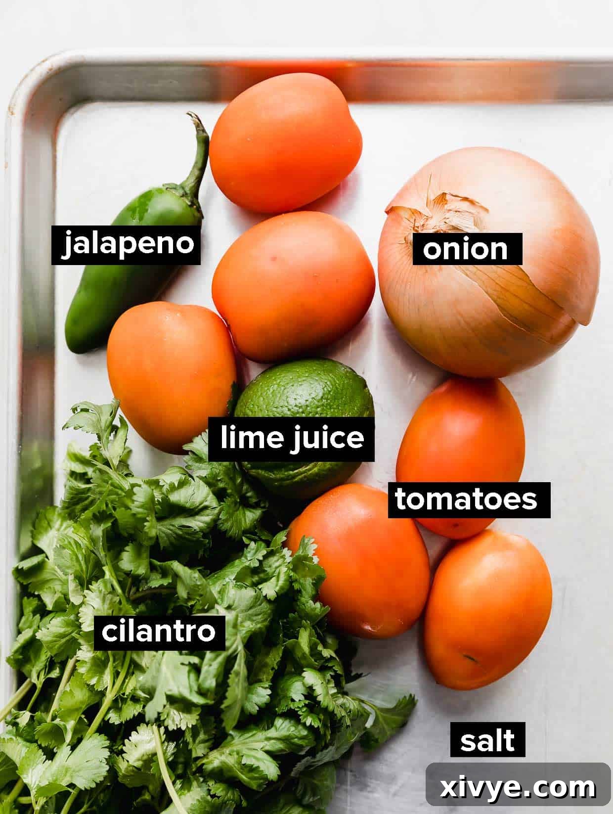 Ingredients used to make pico de Gallo on a silver baking sheet.