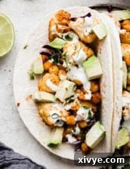 Close up photo of avocado topped Roasted Cauliflower Tacos on a white background.