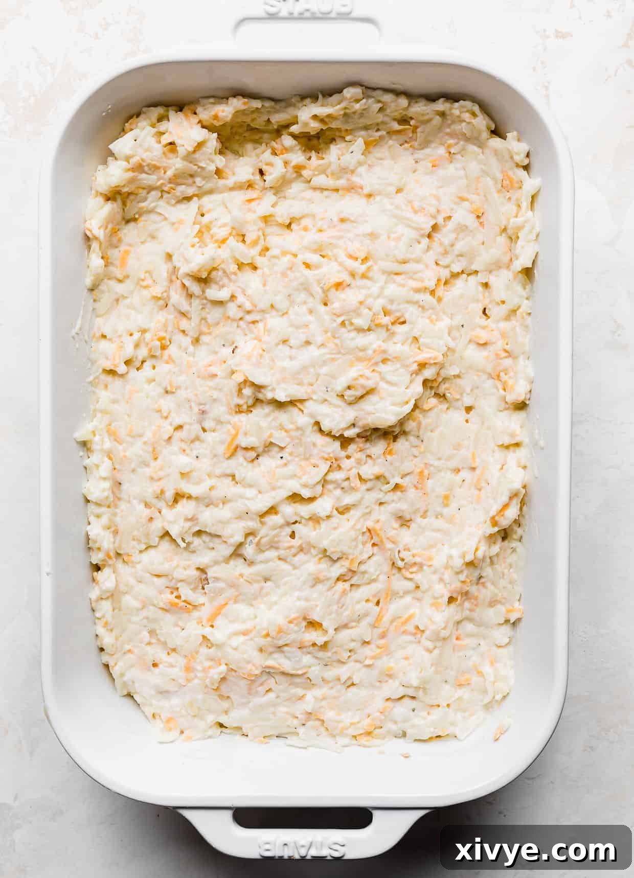 Golden Comfort Bake 6 A white casserole dish filled with leveled Funeral Potatoes mixture, ready for the topping.