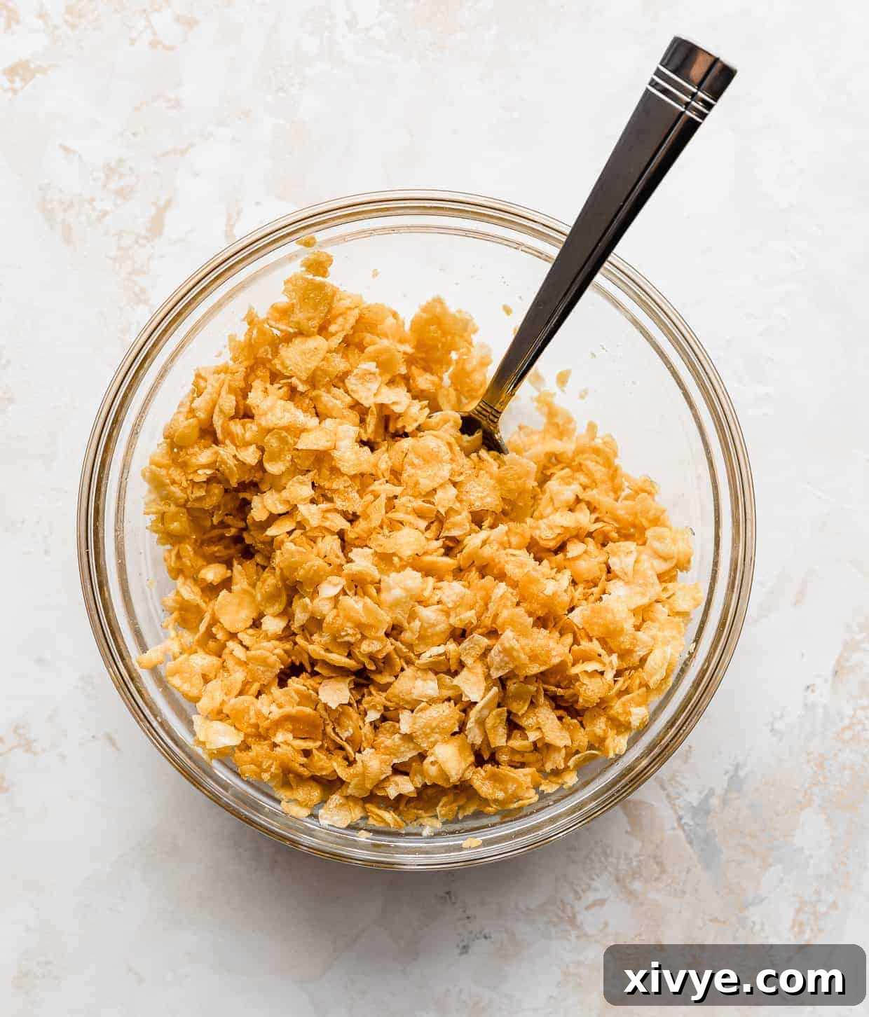 Golden Comfort Bake 7 A glass bowl containing lightly crushed cornflakes, glistening with melted butter, ready to top the casserole.