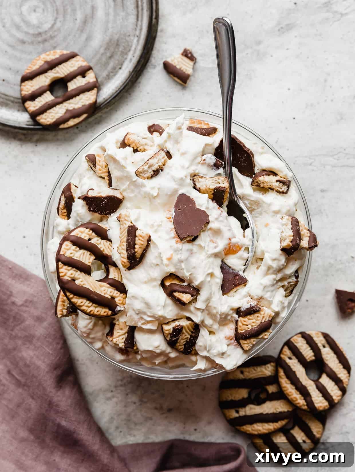 A large bowl full of Cookie Salad against a grey background surrounded by fudge stripe cookies.