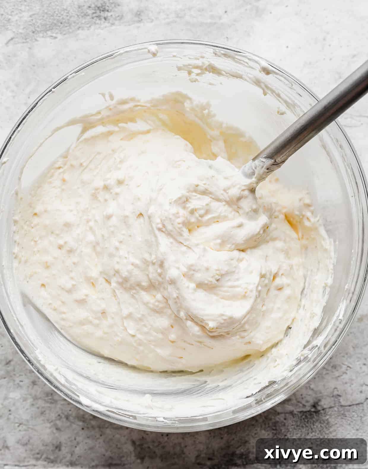 A spatula folding cool whip into vanilla pudding.