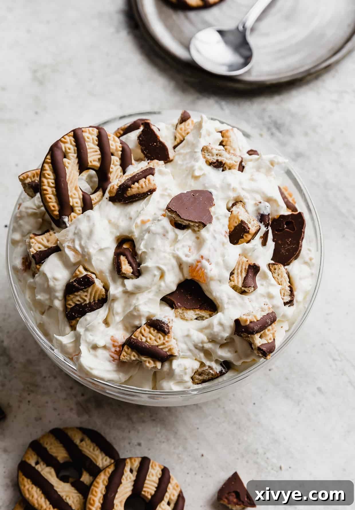 A large glass bowl full of cookie salad topped with crumbled fudge stripe cookies.