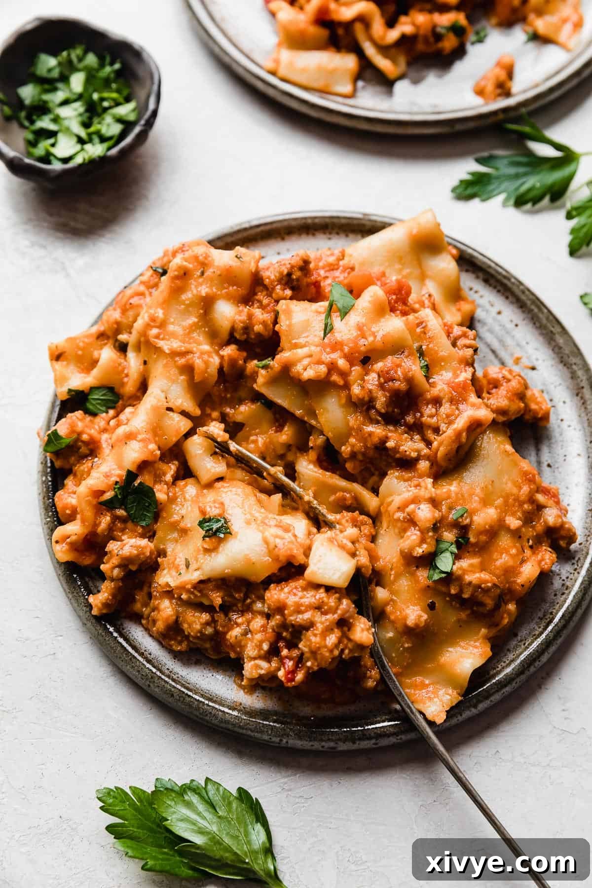 A serving of real simple Slow Cooker Lasagna on a gray plate on a white background.