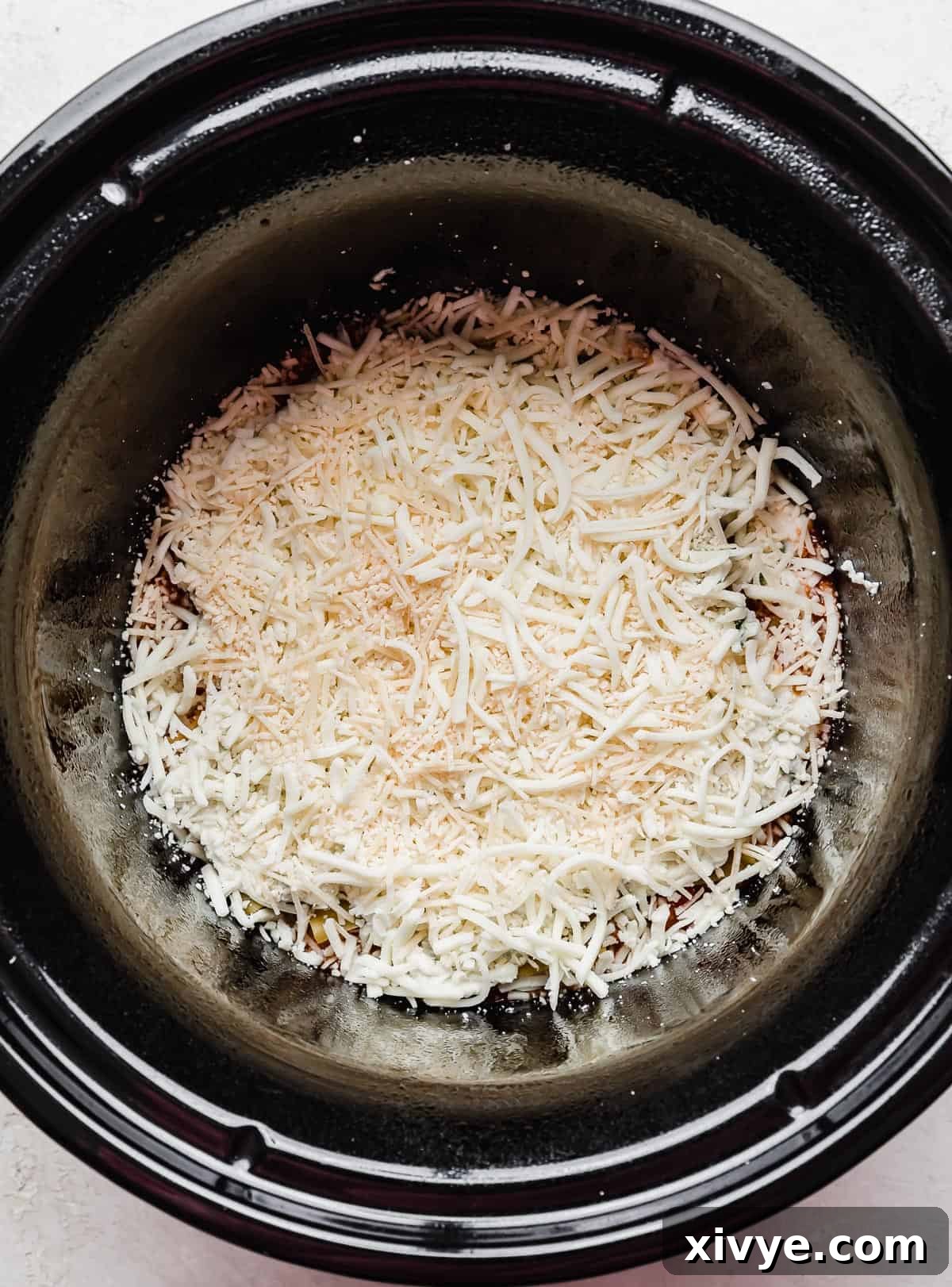Shredded cheese in a round crock pot.
