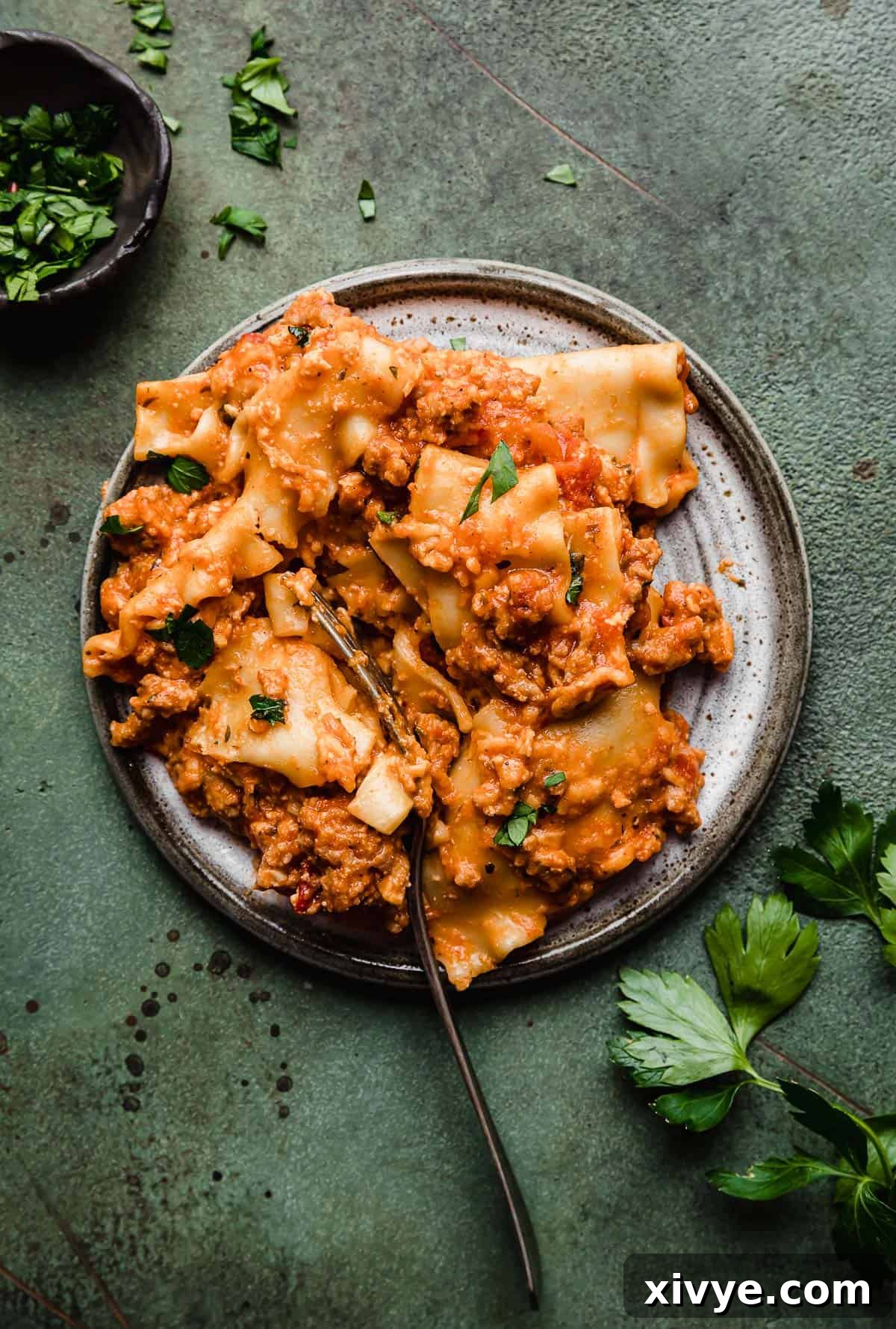 Lazy Slow Cooker Lasagna on a gray plate on a green background.