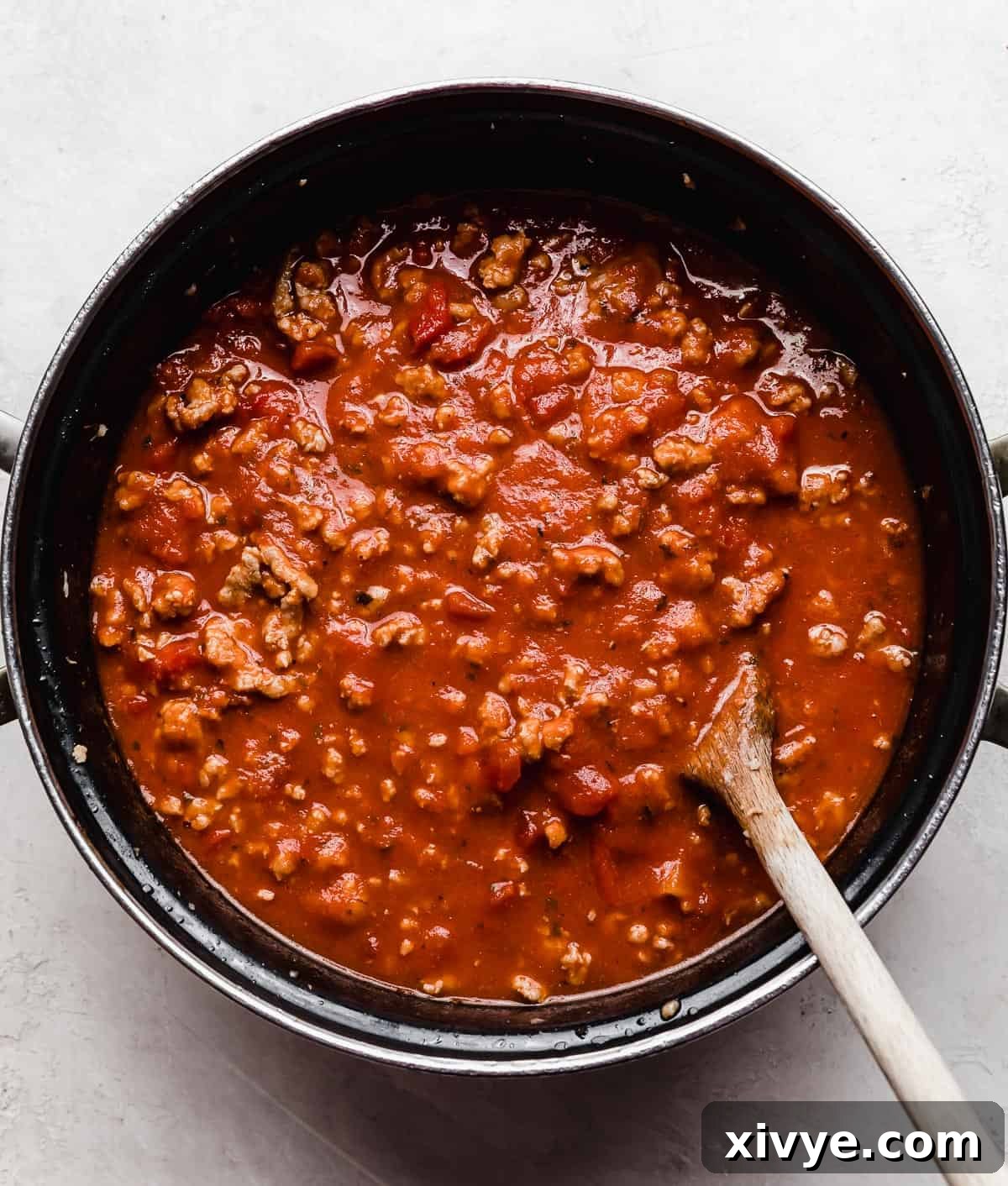 Slow Cooker Lasagna meat sauce with jar marina sauce in a black pot.
