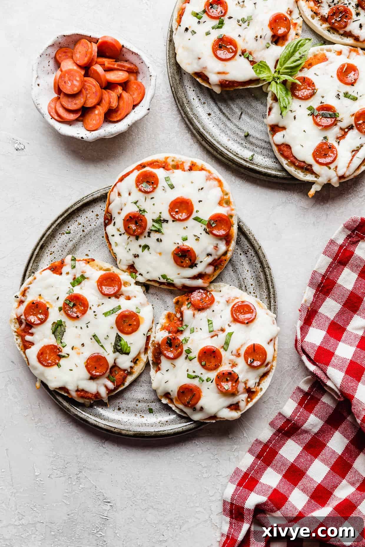 A gray plate with English muffin pizzas on it against a gray background, ready to be enjoyed.