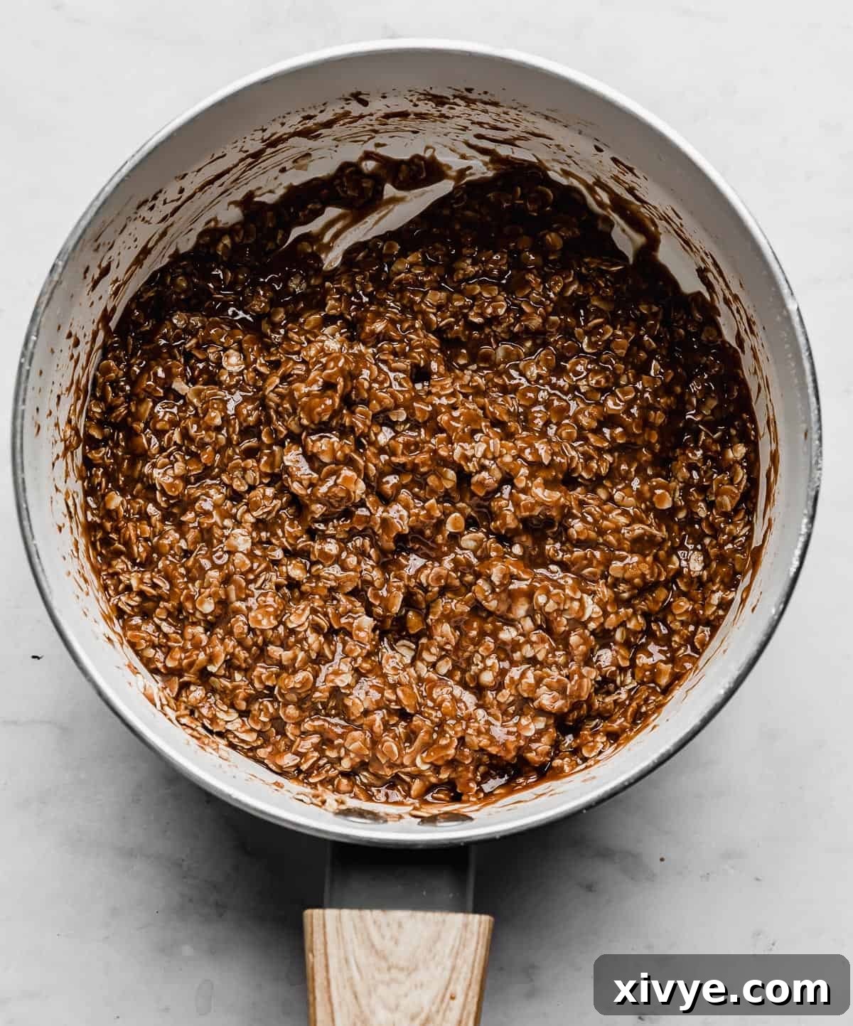 A perfectly mixed chocolate peanut butter no bake cookie mixture in a white pot, ready for portioning.