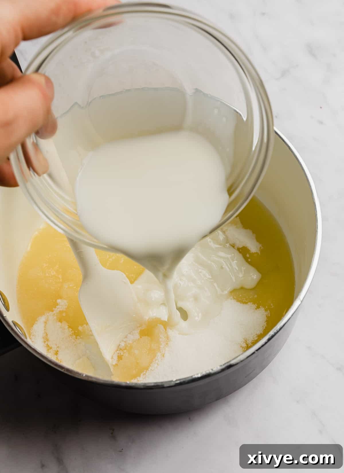 Milk being poured into a white pot containing melted butter and sugar, preparing for a no-bake cookie recipe.