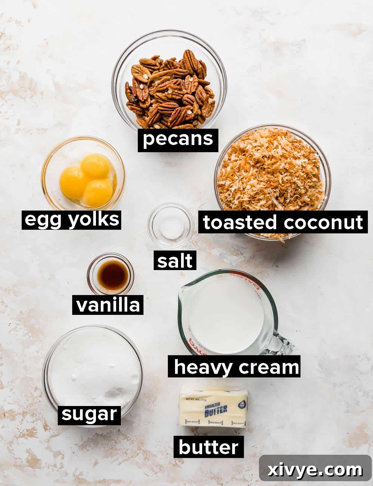 Decadent Coconut Pecan Dream 3 Ingredients used to make coconut pecan frosting, on a white textured background.