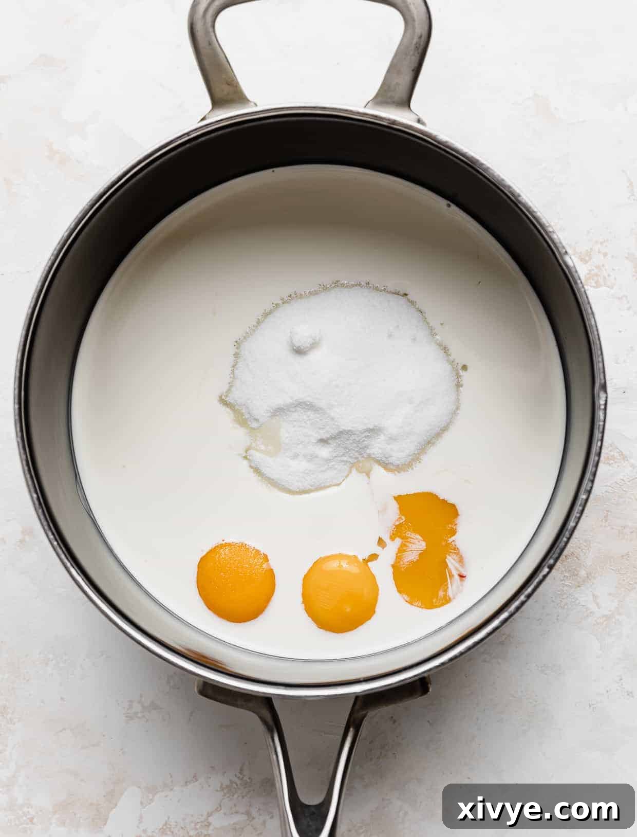 Decadent Coconut Pecan Dream 5 A black saucepan with heavy cream, sugar, and 3 egg yolks in it.