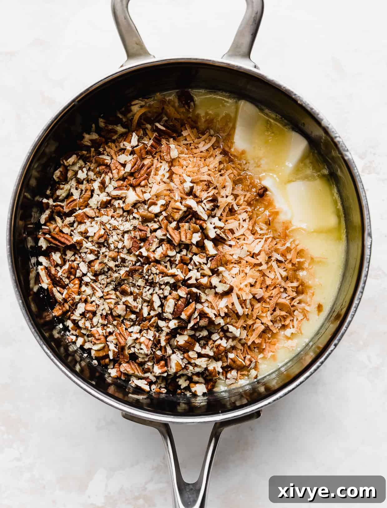 Decadent Coconut Pecan Dream 8 A saucepan with cubed butter, toasted coconut, and chopped pecans in it.