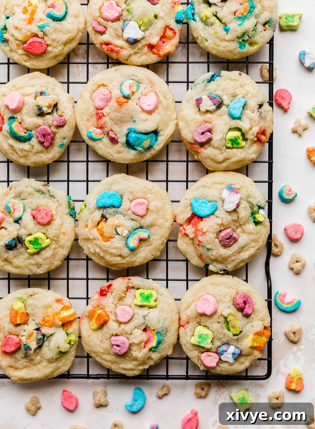 Baked sugar cookies on a black wire rack with lucky charms marshmallows baked into the cookies. 