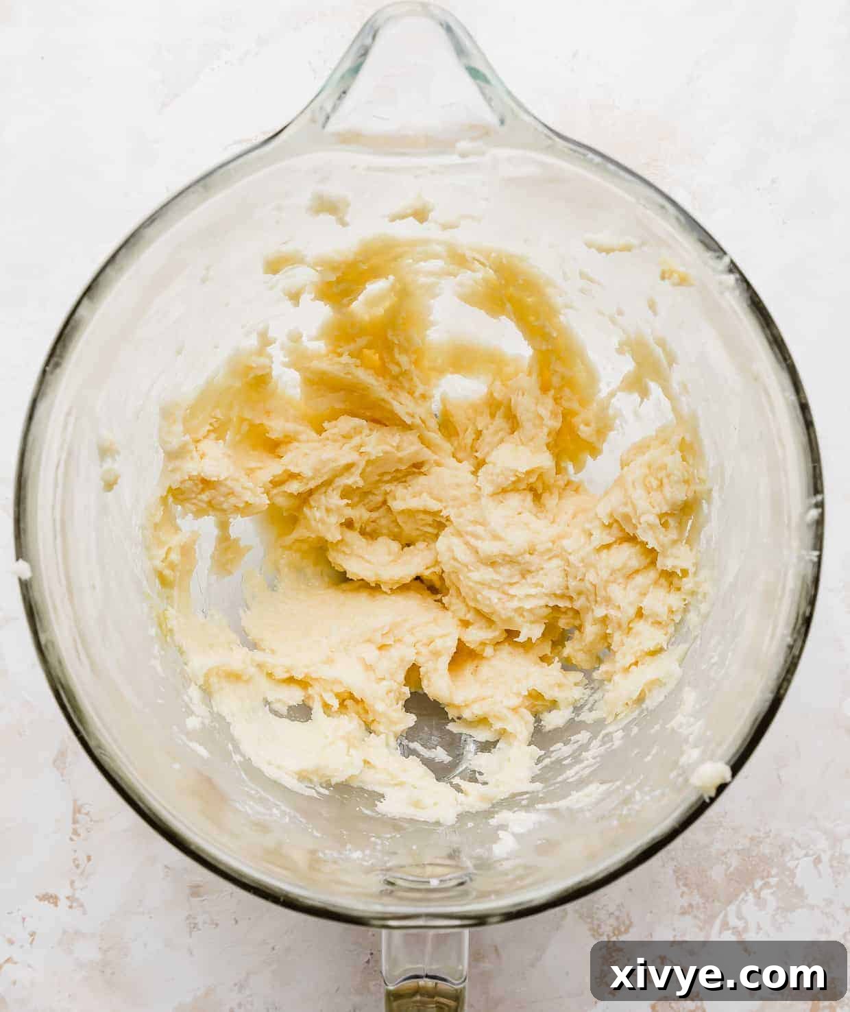 Overhead photo of a glass mixing bowl with creamed sugar cookie dough in it.