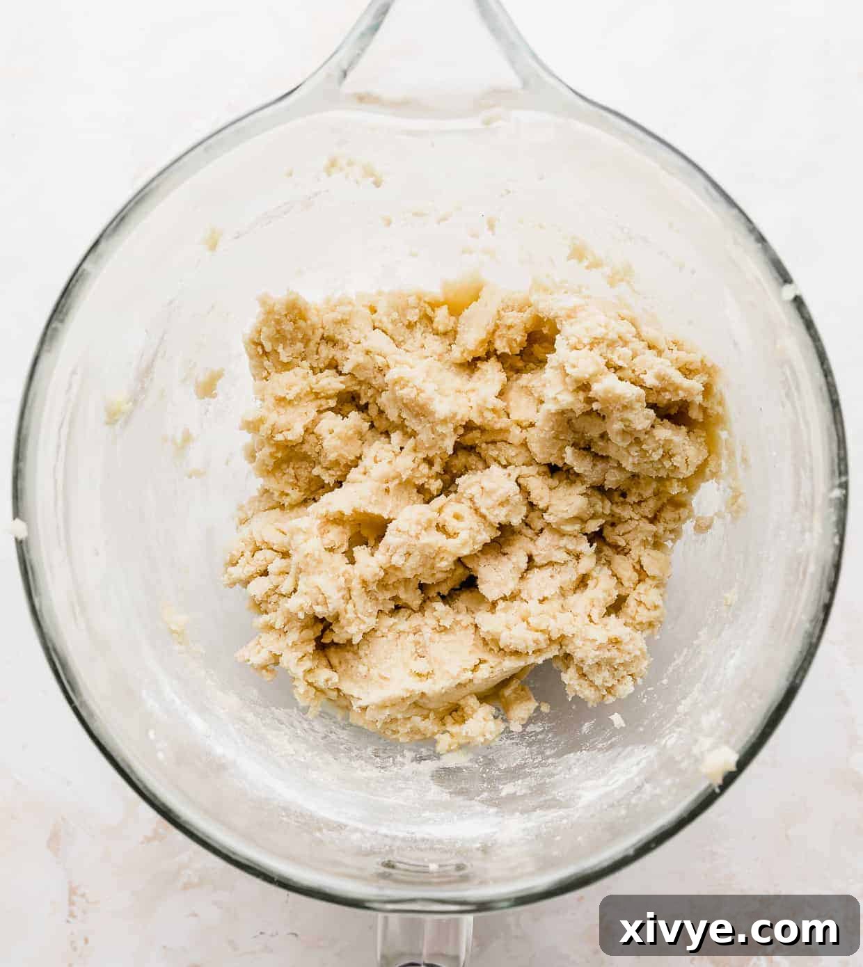 Sugar cookie dough in a glass mixing bowl against a white background.