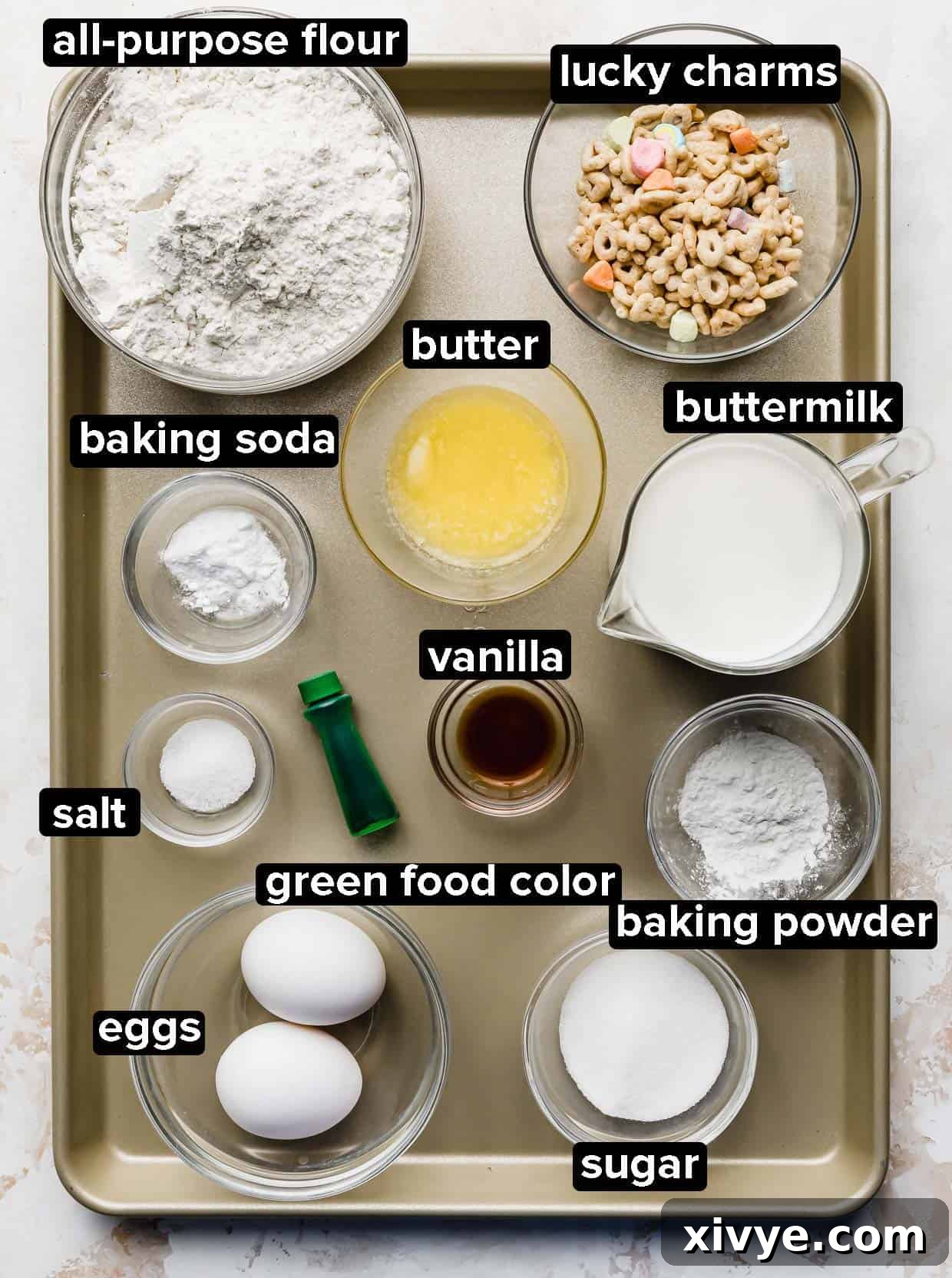 Ingredients used to make green St. Patrick's Day Pancakes portioned into glass bowls on a bronze baking sheet.