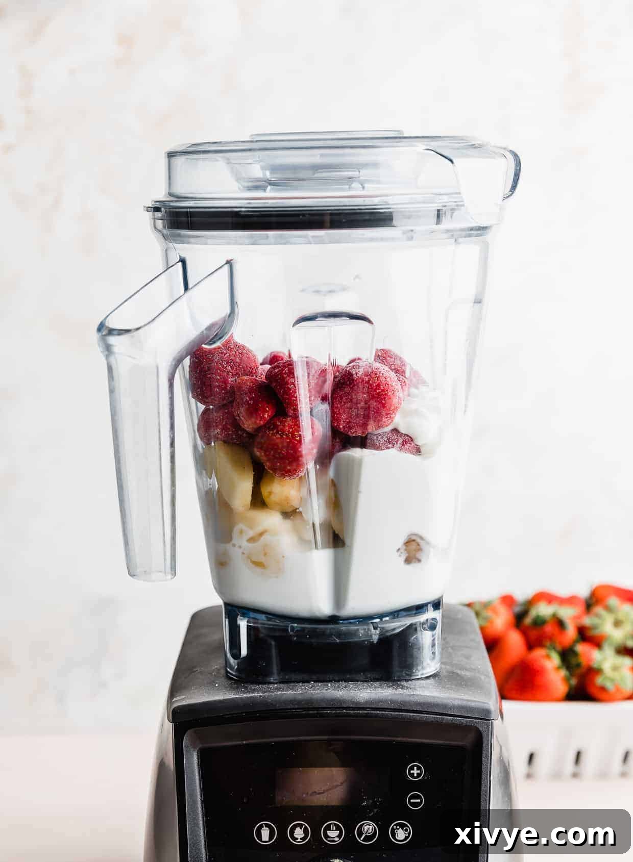 Tropical Strawberry Pineapple Smoothie 6 A Vitamix blender full of ingredients used to make a pineapple and strawberry smoothie against a white background.