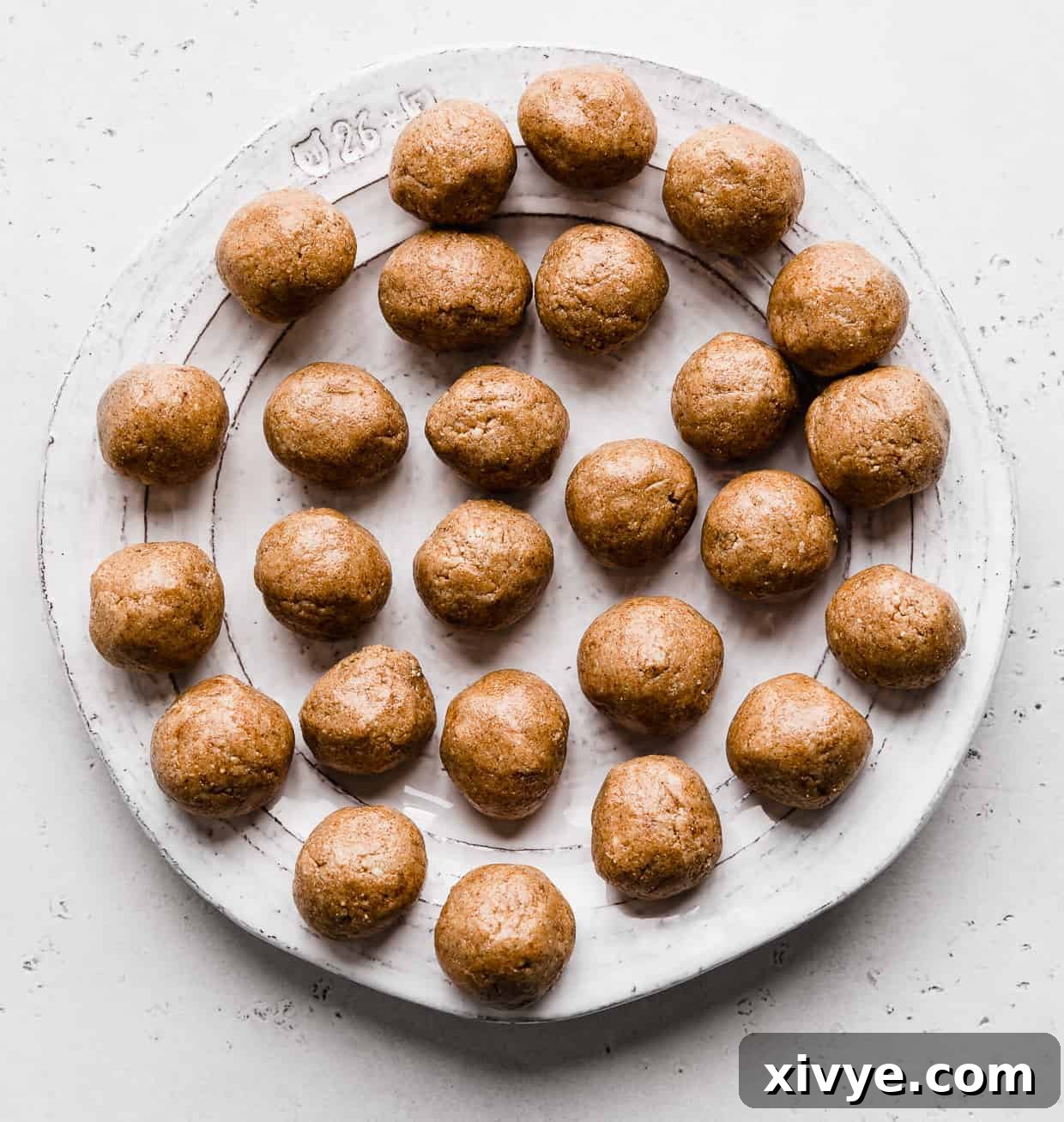 A white plate full of brown Snickerdoodle Energy Bites against a light gray background.