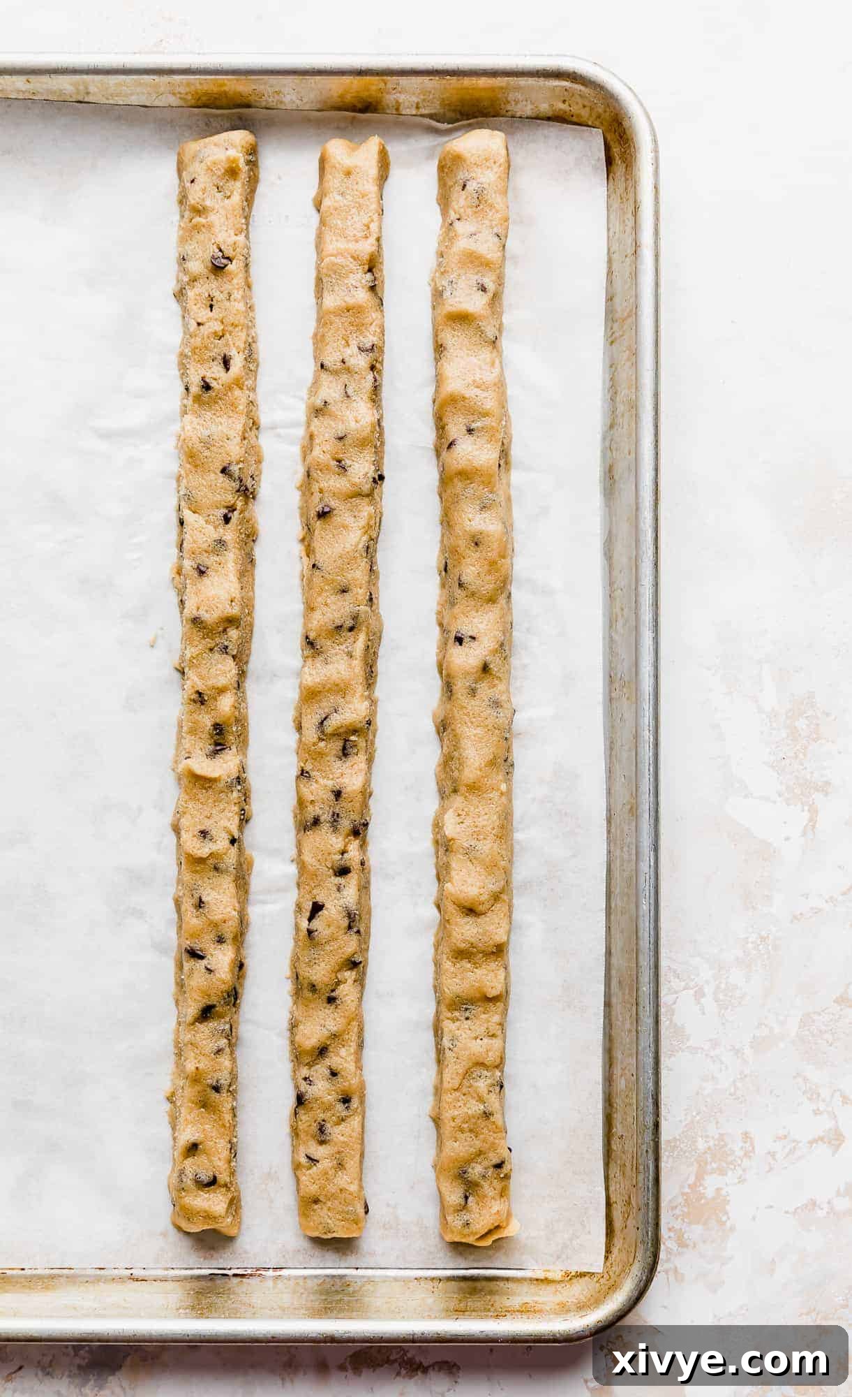 Ben and Jerrys Irresistible Cookie Dough Bites 12 3 ropes of edible cookie dough on a baking sheet against a white background.
