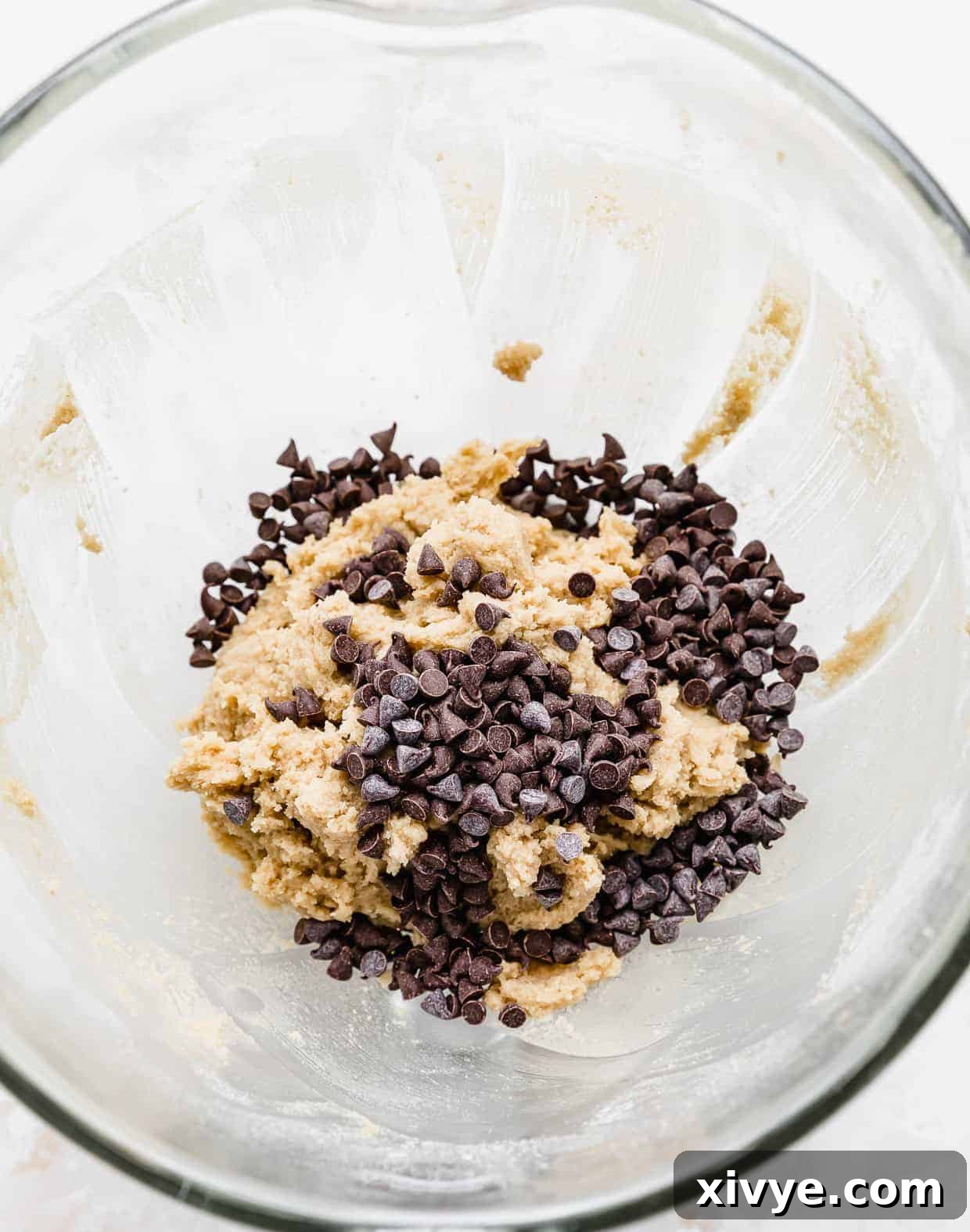 Ben and Jerrys Irresistible Cookie Dough Bites 9 Mini chocolate chips added to a glass bowl with edible cookie dough in it.