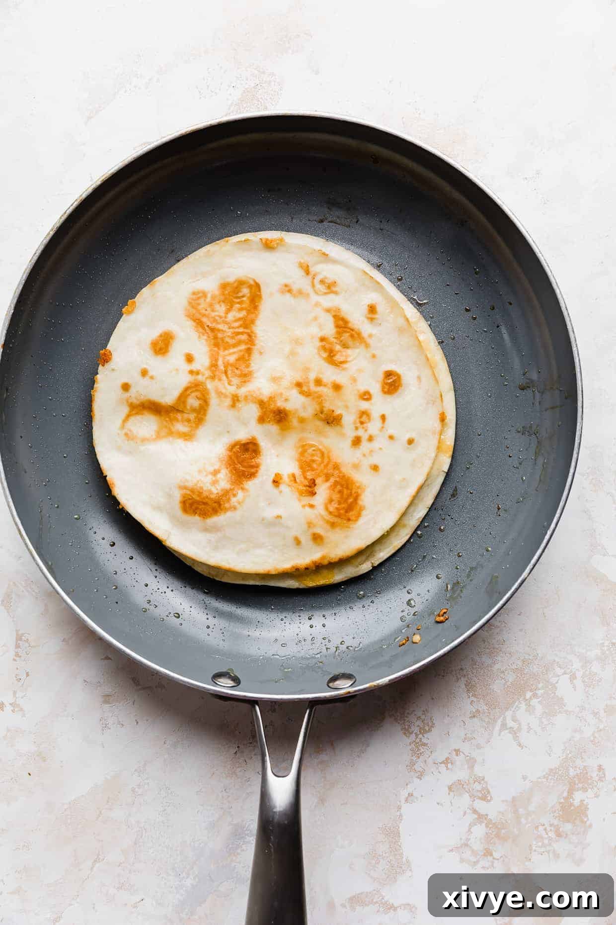 A crispy golden cheese quesadilla in a frying pan.