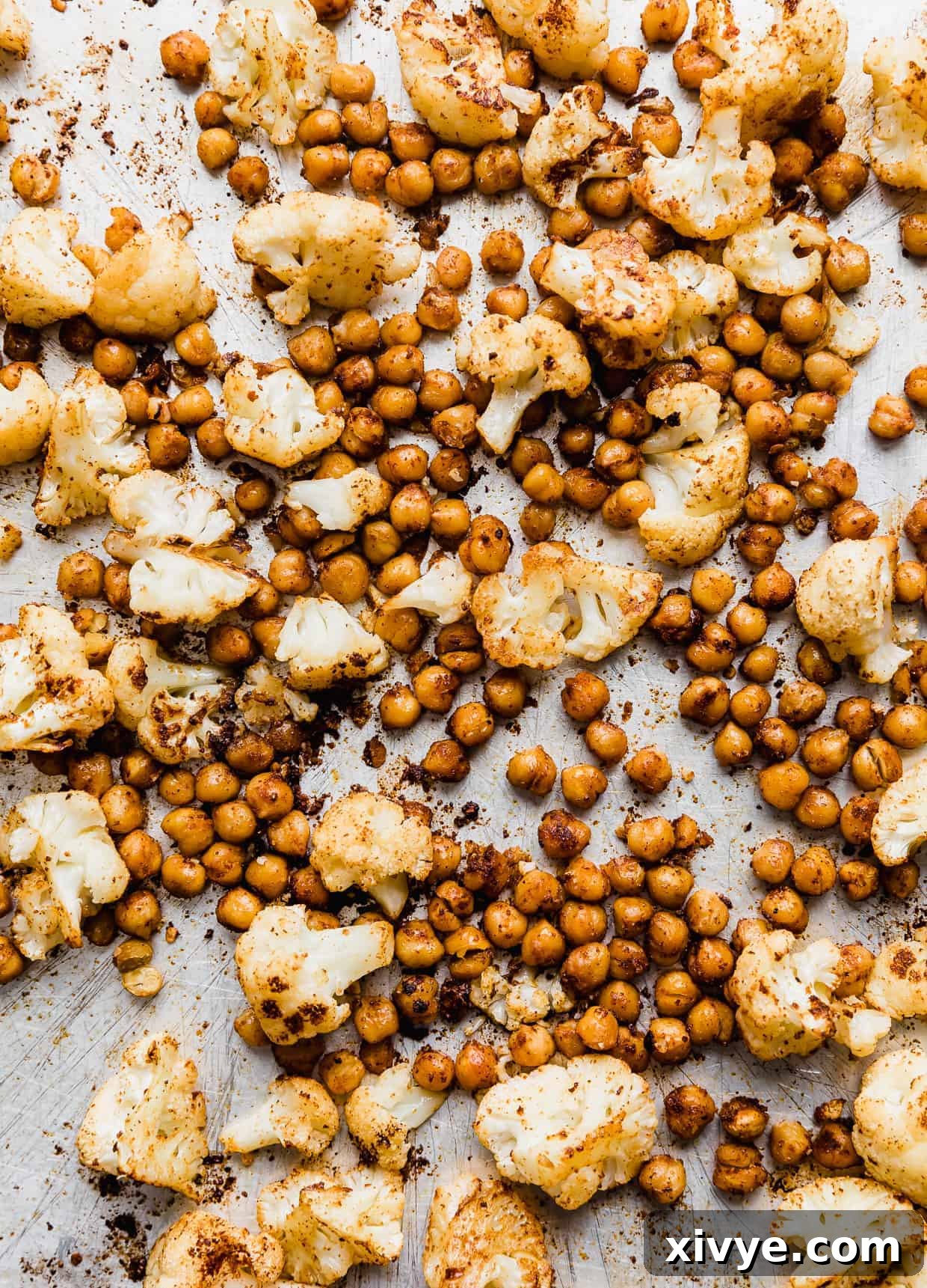 Roasted cauliflower florets and chickpeas on a silver baking sheet.