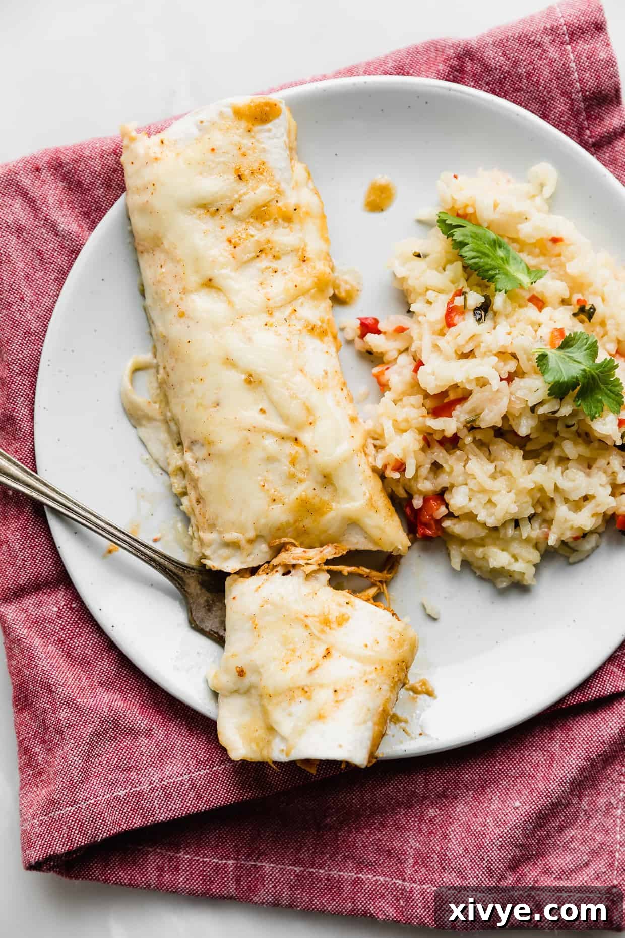 Golden Honey Lime Chicken Enchiladas 2 A white plate with a perfectly baked Honey Lime Chicken Enchilada, with a fork cutting into a portion, revealing the cheesy, flavorful filling.