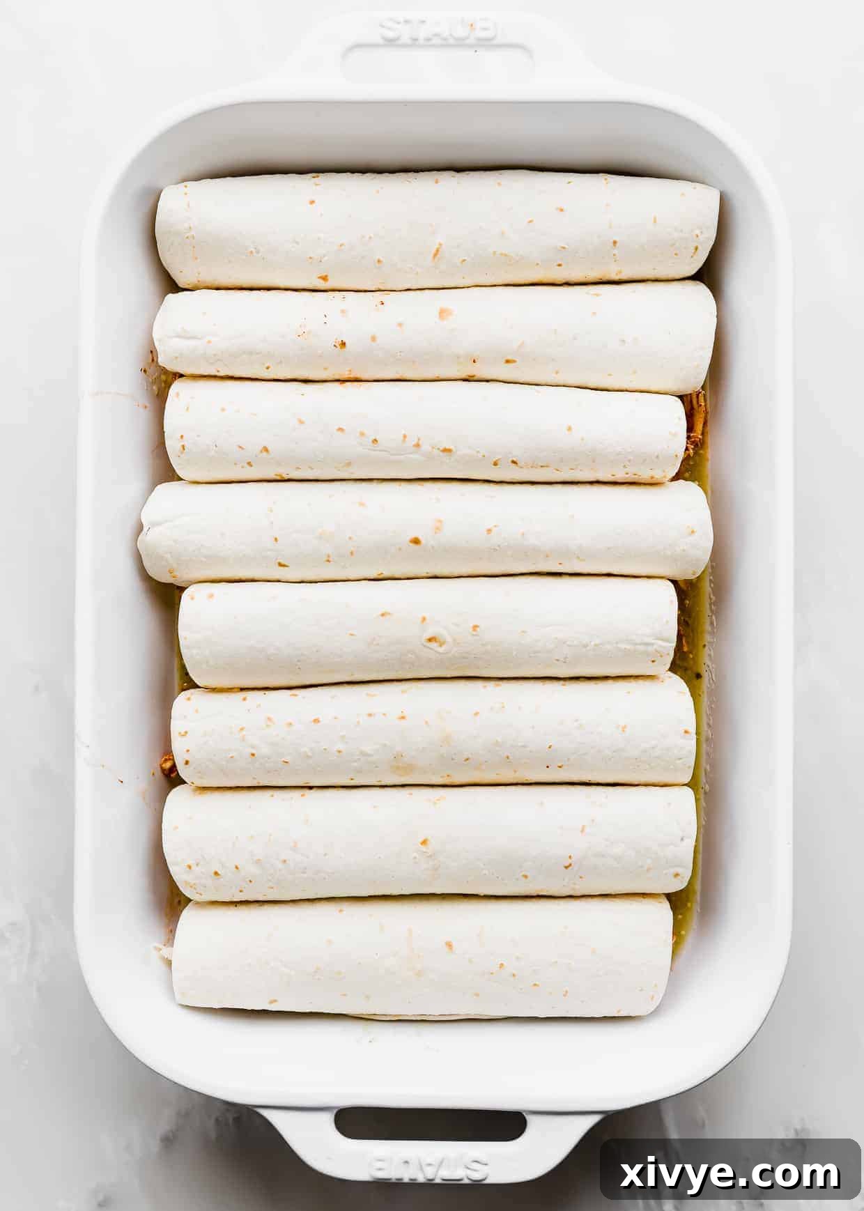 Golden Honey Lime Chicken Enchiladas 5 Eight rolled up enchiladas in a white casserole dish.
