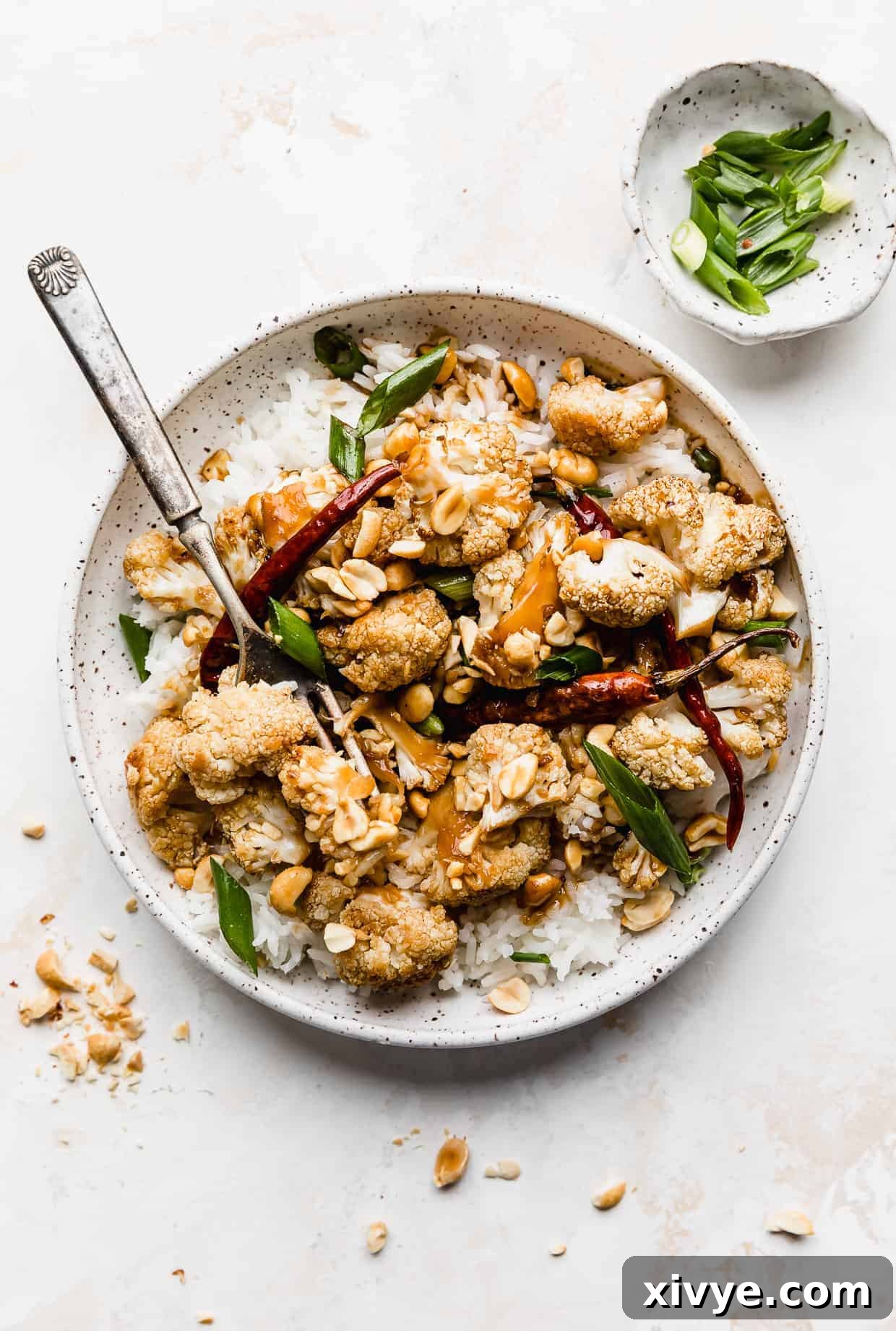 A white plate full of Kung Pao Cauliflower against a white background.