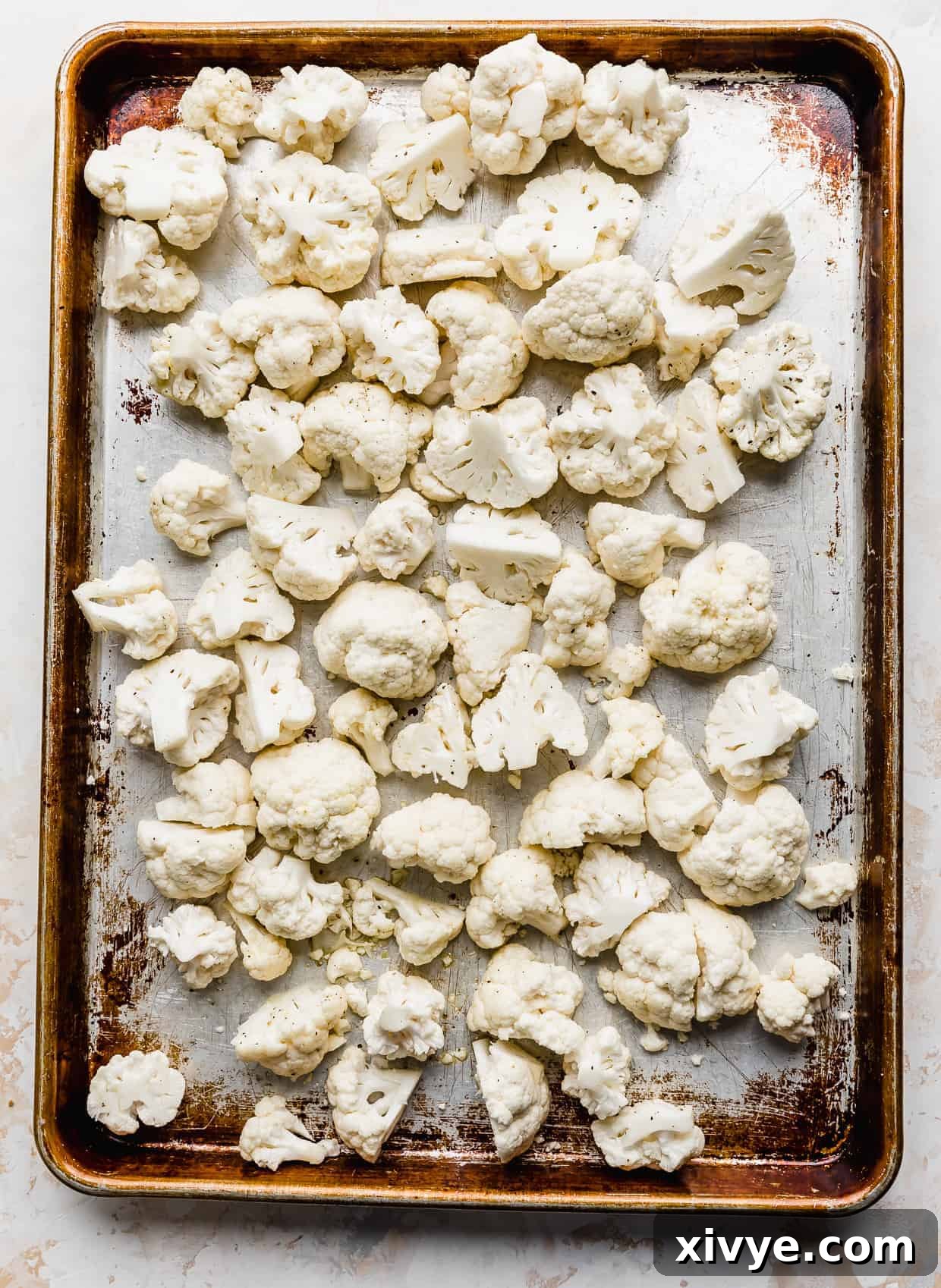 A baking sheet with raw cauliflower florets on it. 