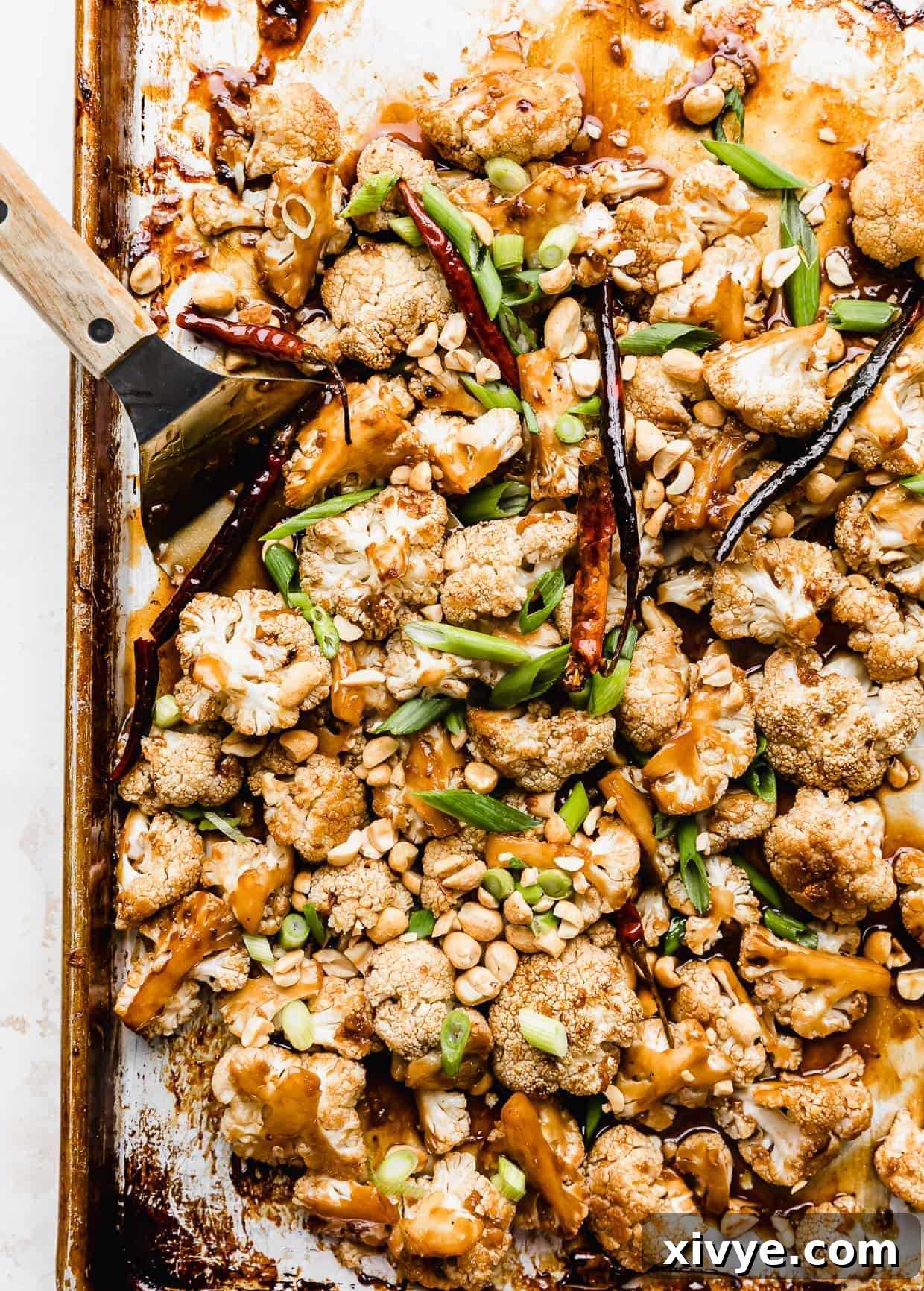 Kung Pao Cauliflower on a baking sheet with sliced green onions and peanuts overtop. 
