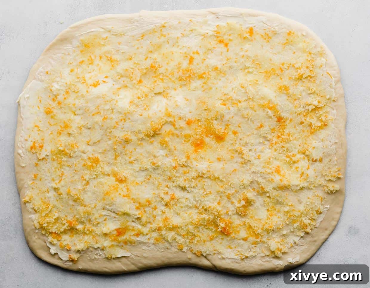 An orange sugar mixture spread over a rectangle sheet or rolled out dough.