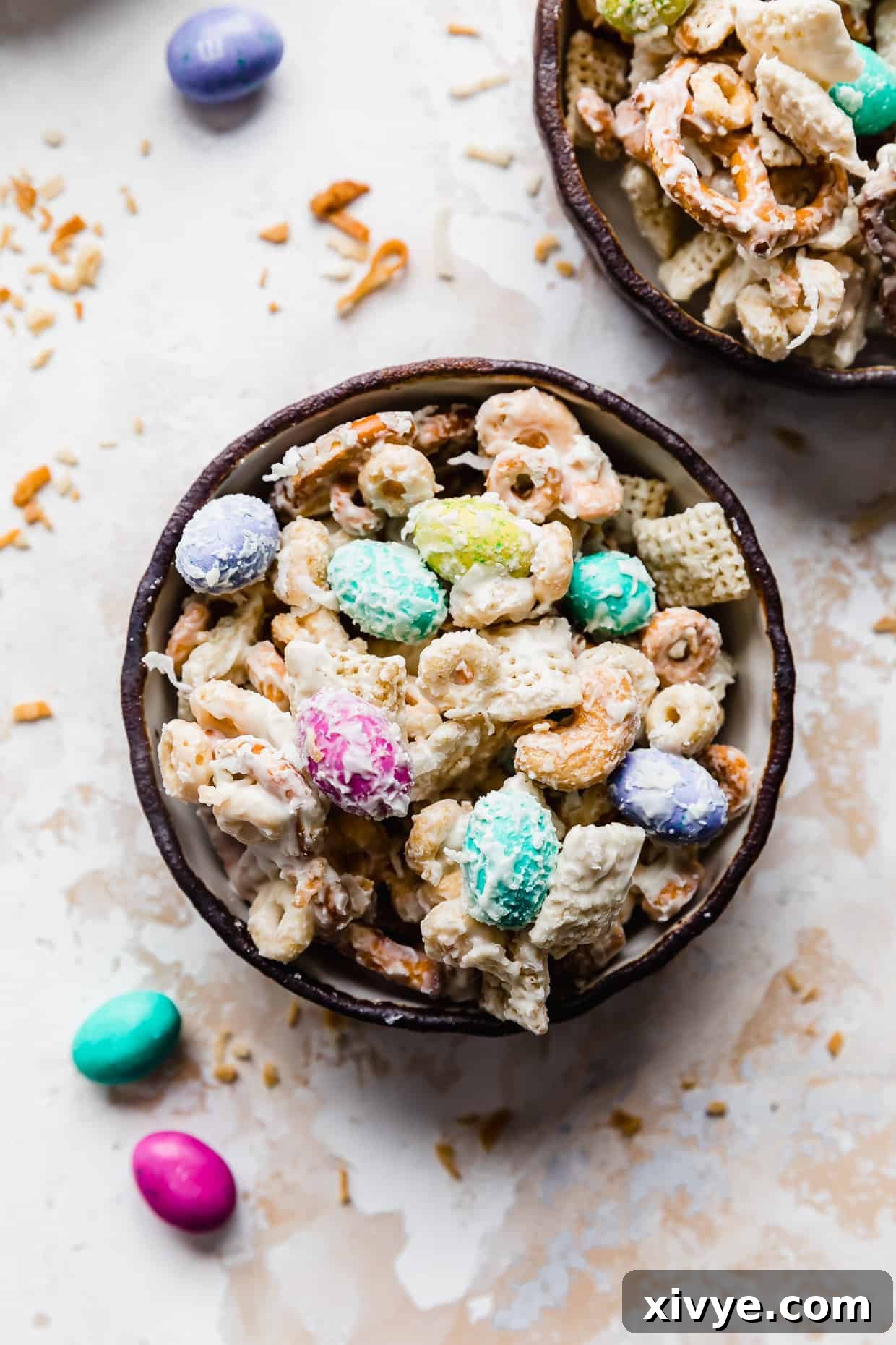 Easter Bunny Crunch Mix 2 A black rimmed bowl full of 'bunny bait' trail mix against a white background, showcasing colorful M&M's, pretzels, and cereal.