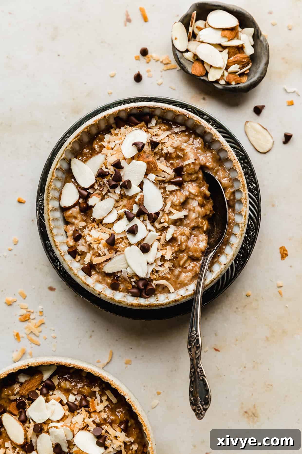 A bowl full of Almond Joy Oatmeal topped with sliced almonds, toasted coconut, and chocolate chips.