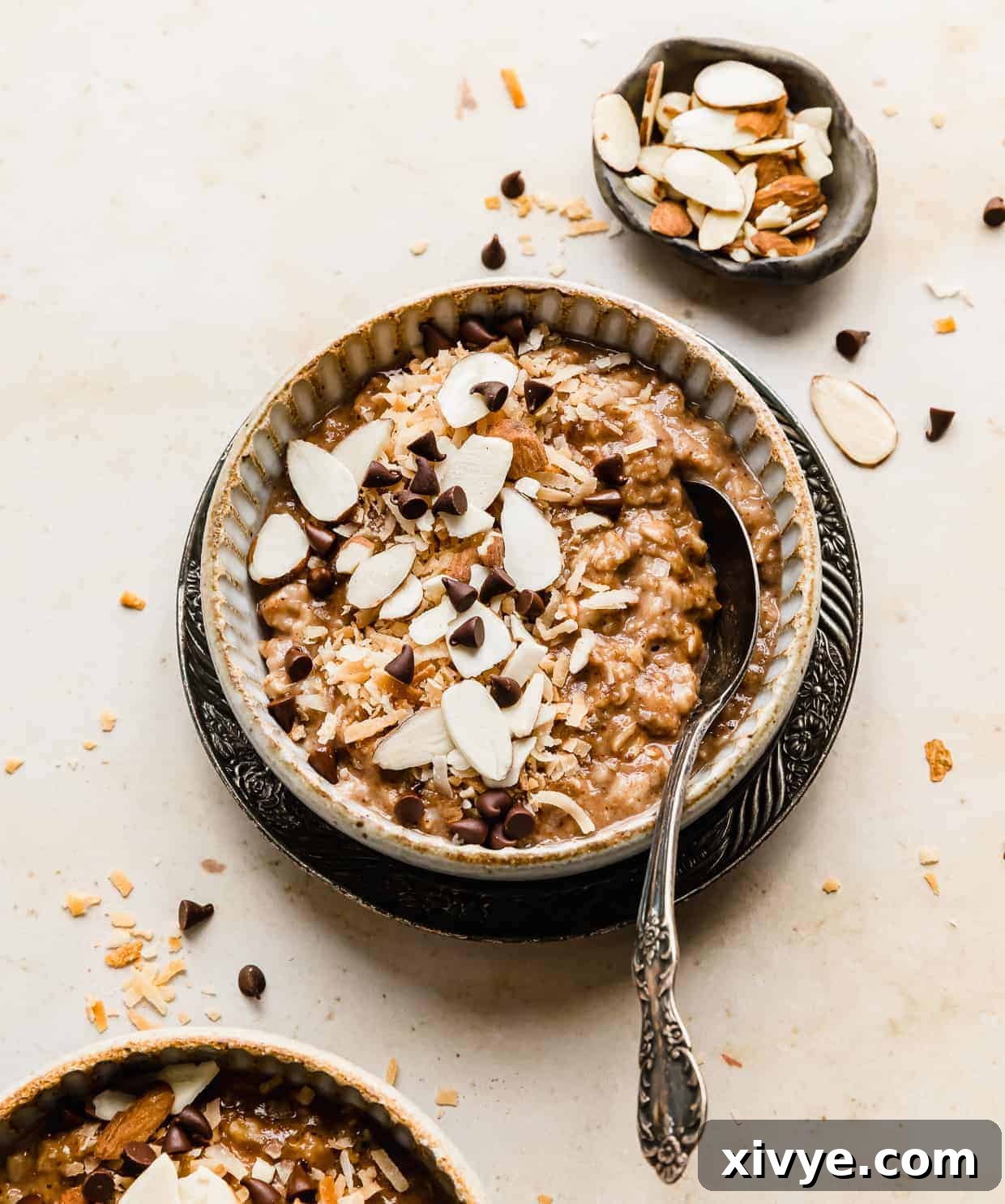 A bowl of almond joy oatmeal topped with sliced almonds and choc chips. 
