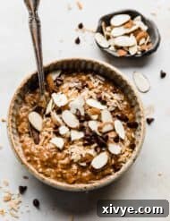 A bowl with almond joy oatmeal topped with coconut, almonds, and chocolate chips.
