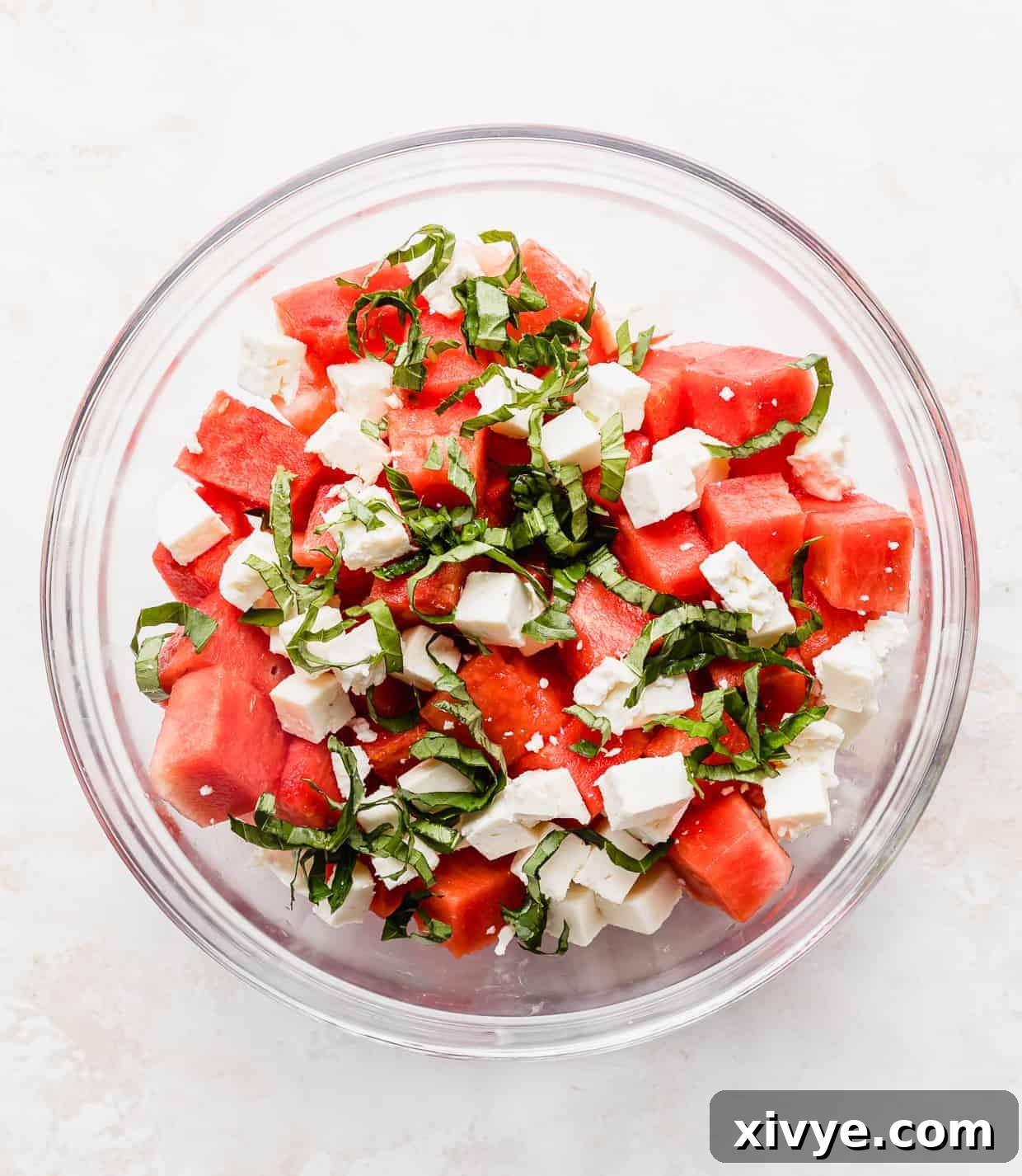 Sweet and Savory Watermelon Feta Basil Salad 3 A glass bowl with chopped watermelon, basil, and feta in it.