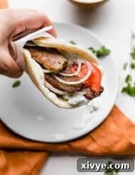 Tender Lamb Gyros 10 A hand holding up a greek lamb gyro in a flat bread.