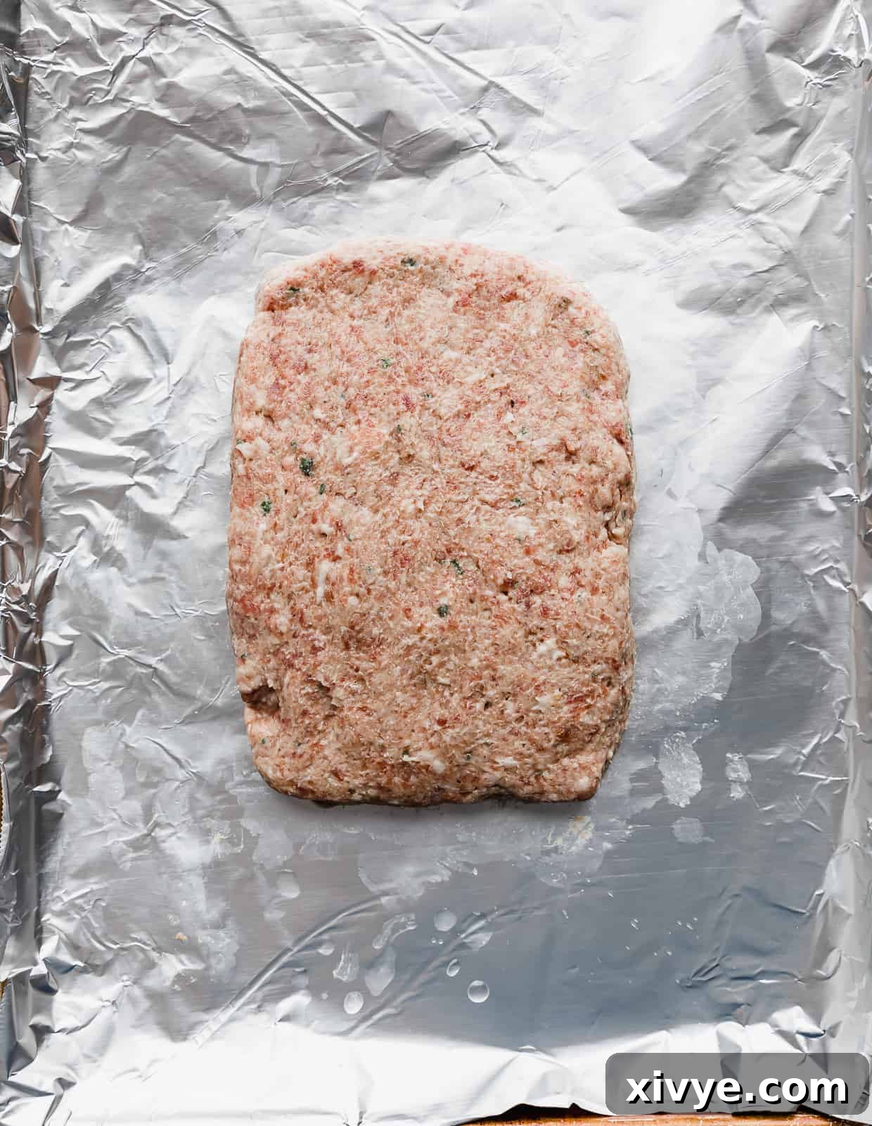 Tender Lamb Gyros 6 Raw lamb gyro meat on a foil lined baking sheet, shaped in a rectangle.