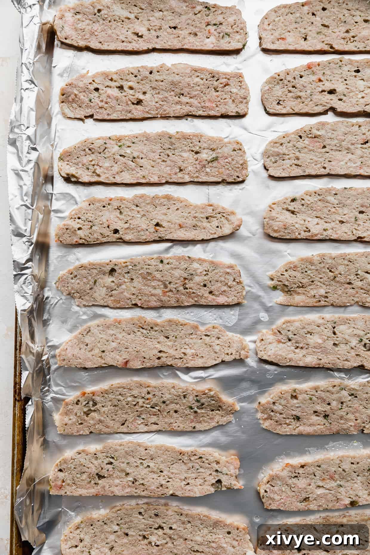 Tender Lamb Gyros 7 Thinly sliced pieces of lamb meat on a foil lined baking sheet.