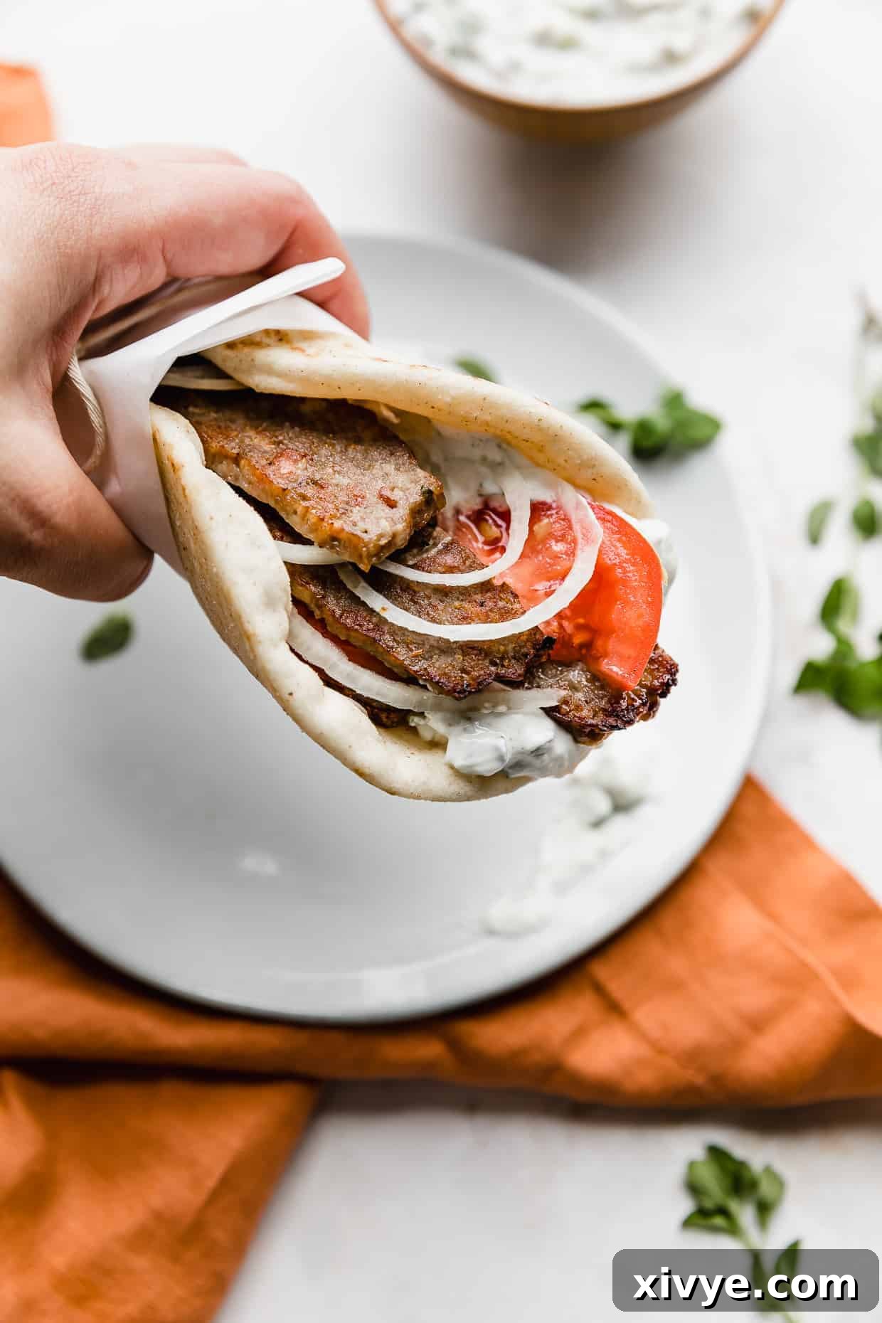 Tender Lamb Gyros 9 A hand holding up a greek lamb gyro in a flat bread.