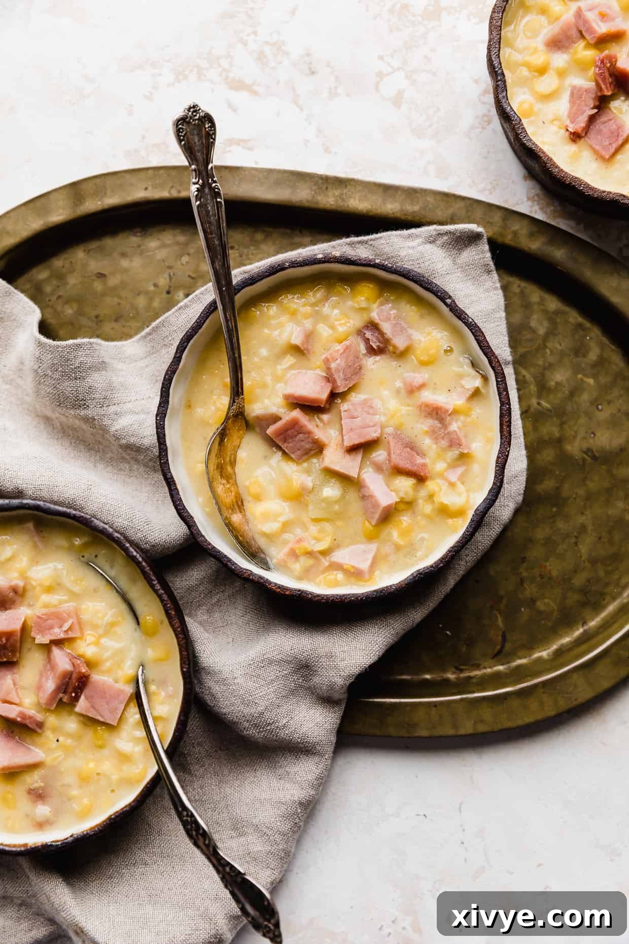 Creamy Ham and Sweet Corn Chowder 2 Three bowls of Ham and Corn Chowder, with one bowl on a bronze platter.