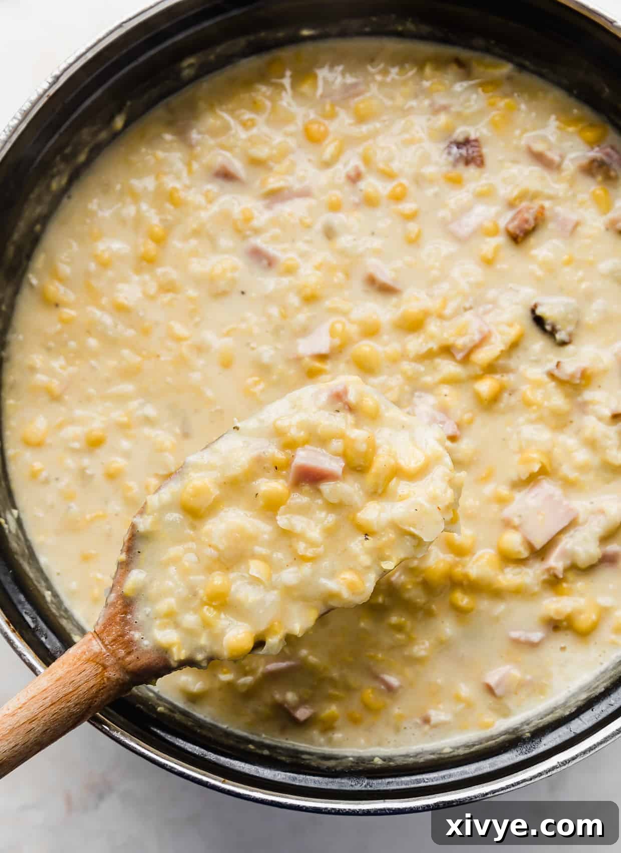 Creamy Ham and Sweet Corn Chowder 11 A wooden spoon scooping up homemade Ham and Corn Chowder.