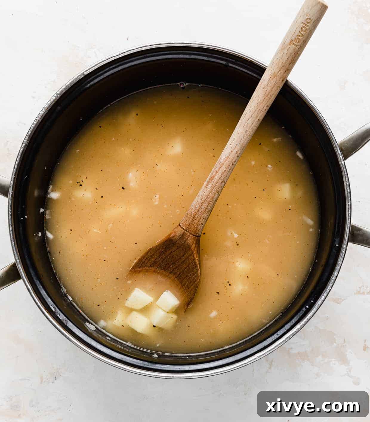 Creamy Ham and Sweet Corn Chowder 6 A pot with chicken broth and diced potatoes in it.