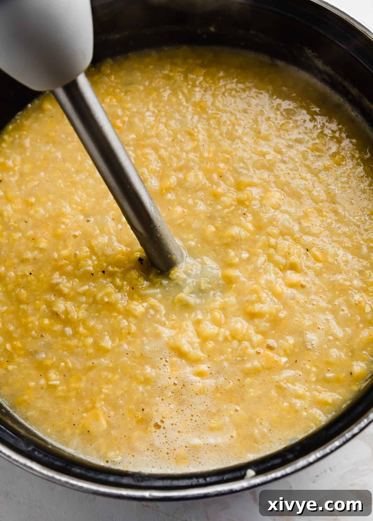 Creamy Ham and Sweet Corn Chowder 9 An immersion blender in a large pot full of cooked corn and potatoes for making Ham and Corn Chowder.