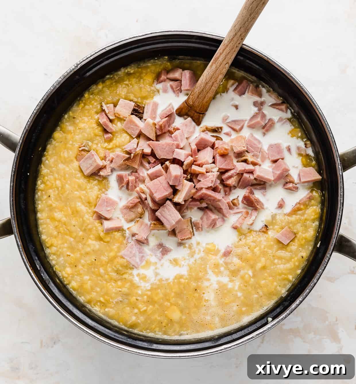 Creamy Ham and Sweet Corn Chowder 10 A large pot full of corn chowder, with diced ham and heavy cream placed overtop of the chowder.