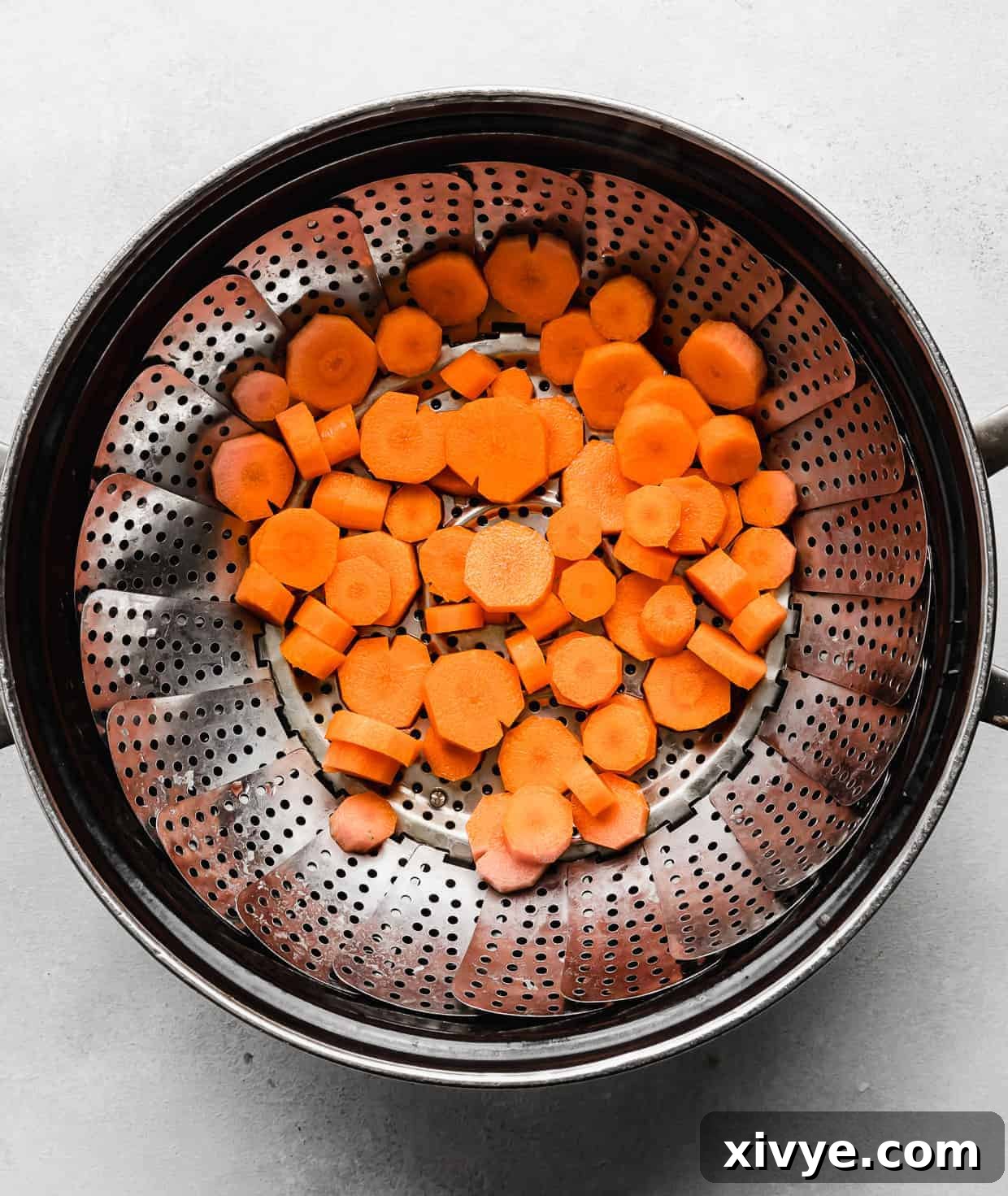 Sliced carrots in a steamer basket that's nestled in a large pot. 
