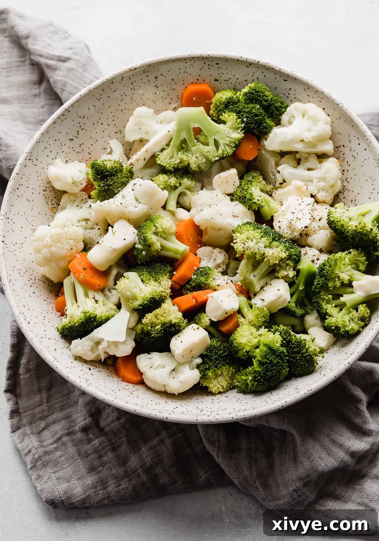Buttered Vegetables in a large serving bowl with cubes of butter over the top.