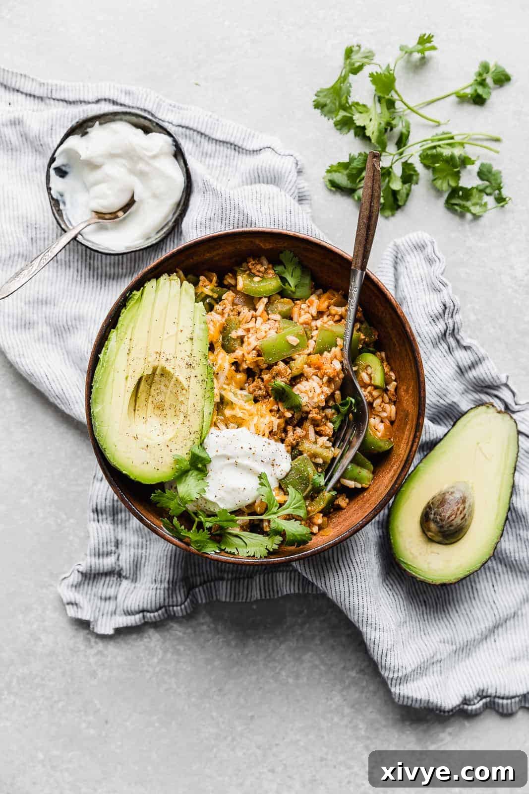 Unstuffed Pepper Casserole 7 Deconstructed Stuffed Peppers in a brown bowl with a sliced avocado and cilantro for garnish.